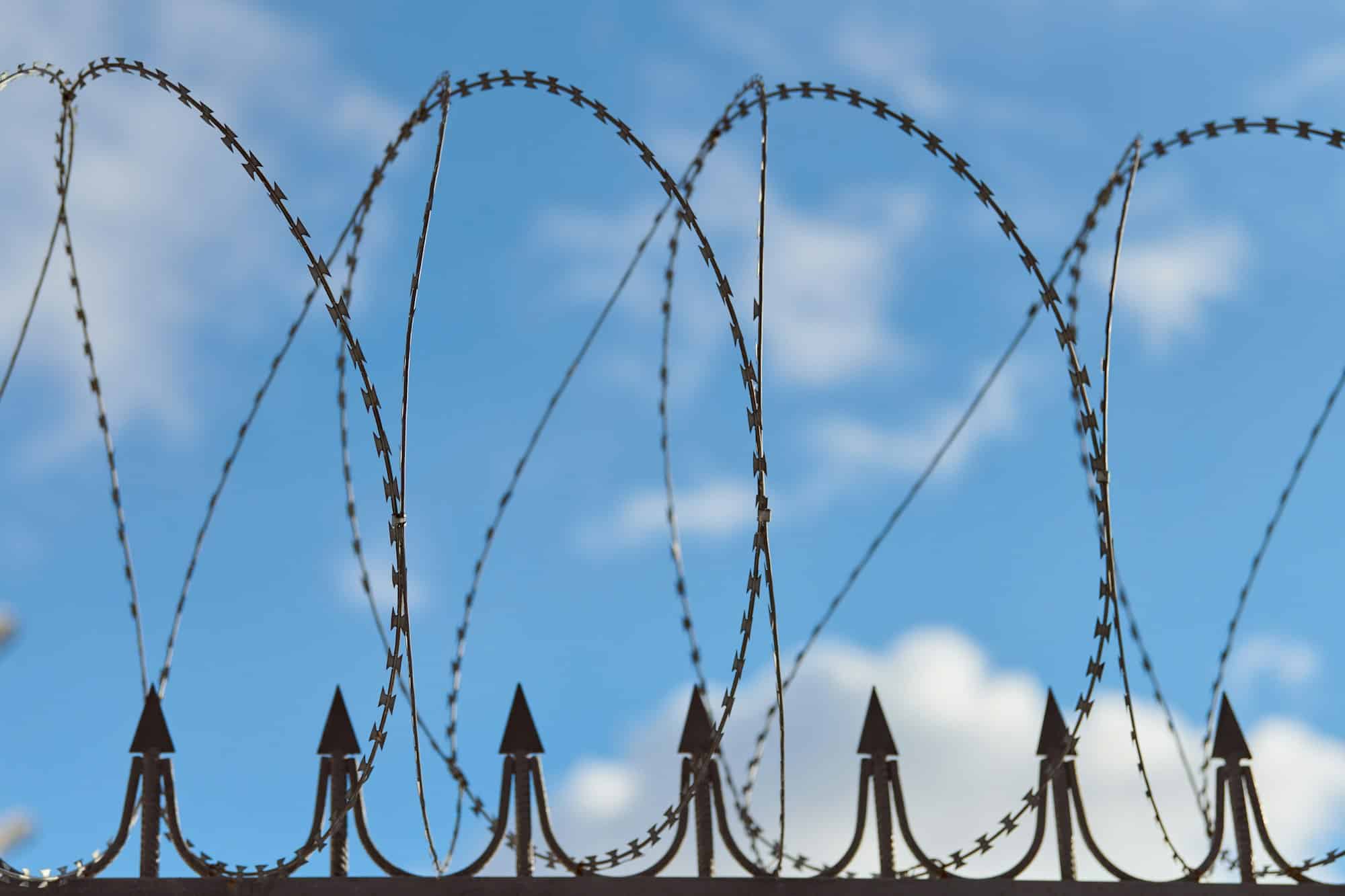 Barbed wire on fence, steel grating fence with barbs